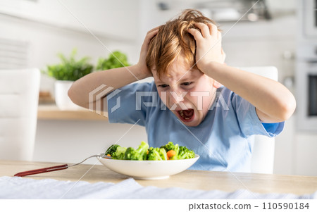 Shocked and upset little boy because he has to eat broccoli for dinner, which he doesn't like 110590184