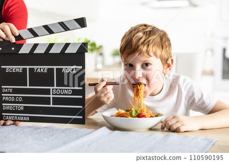 Young talented actor boy in front of the camera eating spaghetti for lunch Young talented actor boy in front of the camera eating spaghetti for lunch 110590195