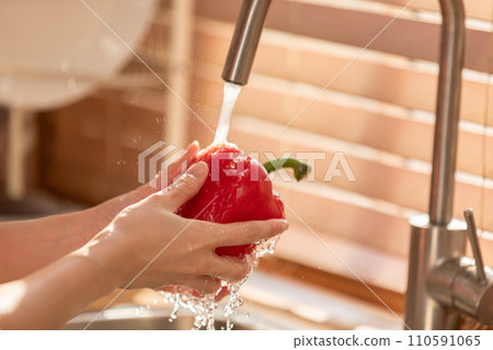 Close up hands washing vibrant bell pepper prepare for healthy eating, cooking, and the joy of creating delicious meals. 110591065