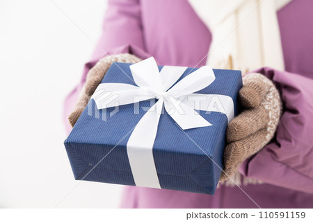 Middle-aged woman in winter clothes holding a present Middle-aged woman in winter clothes holding a present 110591159