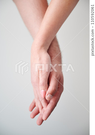 Close up view of hands of sweet couple. Young man and woman holding hands on light neutral background. Concept of love, intimacy, support, and trust. 110592061