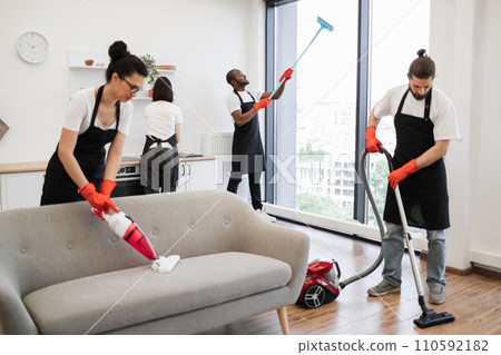 Team of service workers cleaning sofa, carpet, cuisine table and panoramic window. 110592182