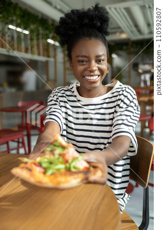 Pretty young dark-skinned woman eating pizza and feeling good Pretty young dark-skinned woman eating pizza and feeling good 110592807