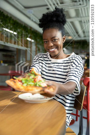 Pretty young dark-skinned woman eating pizza and feeling good 110592833