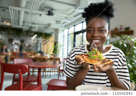 Pretty young dark-skinned woman eating pizza and feeling good 110592842