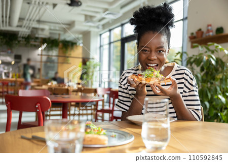 Positive african american woman with a slice of pizza in hands Positive african american woman with a slice of pizza in hands 110592845
