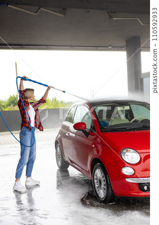 Young woman in checkered shirt washing a car 110592933