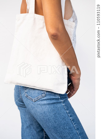 Unrecognizable lady carrying white eco tote bag. Sustainable lifestyle. 110593119