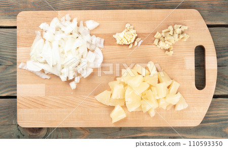 Chopped spices garlic, onions with ginger and pineapple pieces on a cutting board. Chopped spices garlic, onions with ginger and pineapple pieces on a cutting board. 110593350