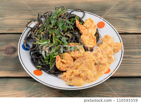 Butter masala with shrimp and black spaghetti garnished with cilantro and pea sprouts. Butter masala with shrimp and black spaghetti garnished with cilantro and pea sprouts. 110593359