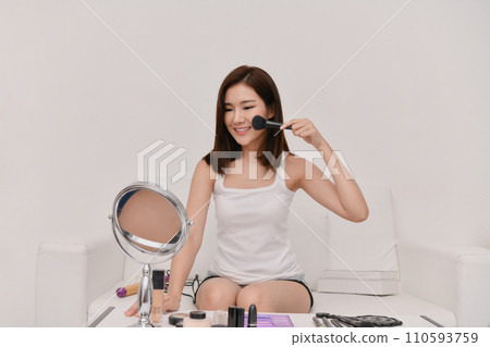 Beautiful girl doing makeup at home. Asian woman taking care of her face. Beautiful girl doing makeup at home. Asian woman taking care of her face. 110593759