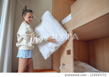 Beautiful woman putting on fresh bed linen in hotel room. Beautiful woman putting on fresh bed linen in hotel room. 110593772