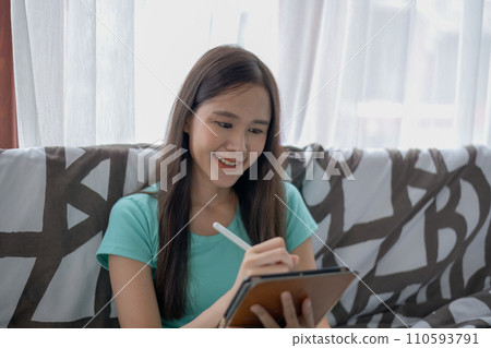 Asian woman using tablet in living room. 110593791