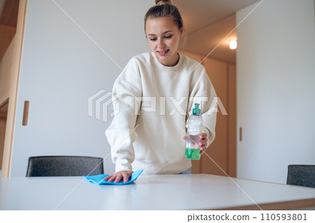 Woman housewife in white sweatshirt cleaning her home using rag and detergent. Woman housewife in white sweatshirt cleaning her home using rag and detergent. 110593801