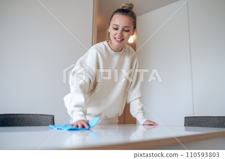 Woman housewife in white sweatshirt cleaning her home and wiping dust. 110593803