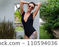 Beautiful european woman in black swimsuit posing outside at villa, on vacation, perfect shape, good body, tanned, fit, wearing trendy brown sunglasses 110594036