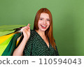 Young red hair woman on green background with shopping bags happy cheerful excited 110594043