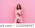 Young beautiful smiling cute romantic woman in trendy summer dress. Carefree woman posing in the street near pink wall. Positive model outdoors in sunglasses. Cheerful and happy. 110594047