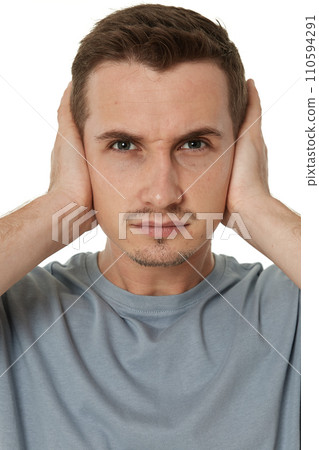 caucasian man in t-shirt covers ears with hands on white background 110594291