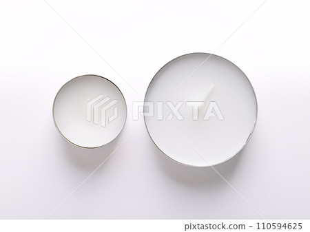 Common tealight and a maxi tealight, from above. Two types of tea lights, also called tea candle or t-lite, with different burning time, and a thin metal cup, so wax can liquefy completely while lit. Common tealight and a maxi tealight, from above. Two types of tea lights, also called tea candle or t-lite, with different burning time, and a thin metal cup, so wax can liquefy completely while lit. 110594625
