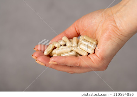 Female hands holding a heap of capsules, collagen, vitamins, pain killers, food supplements pills. Female hands holding a heap of capsules, collagen, vitamins, pain killers, food supplements pills. 110594886