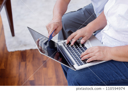 hand of old generation use laptop with credit card in online banking for transfer 110594974