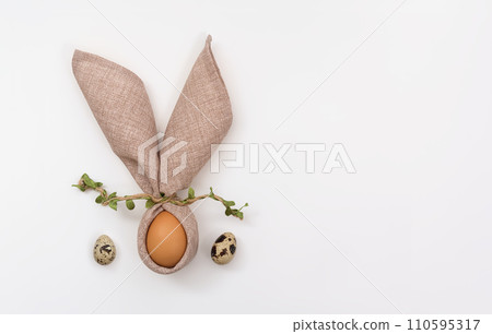 Happy Easter greeting card. Bunny made of a napkin and egg on white background. Quail eggs. Postcard template in minimalist style. Copy Space, flat lay 110595317