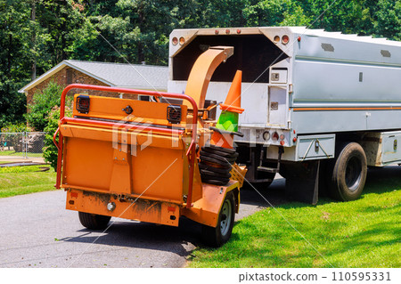 Wood chipper machine releases ground tree branches that are shredded into wood chips Wood chipper machine releases ground tree branches that are shredded into wood chips 110595331