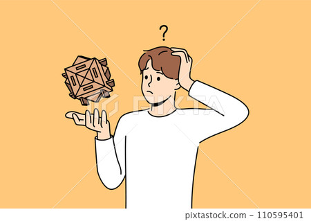Confused man with wooden puzzle scratches head, wondering how to solve difficult problem 110595401