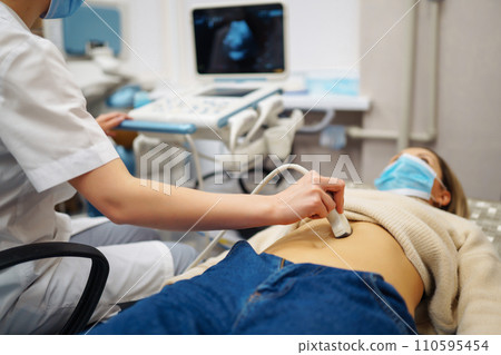 Doctor makes patient women abdominal ultrasound. Ultrasound Scanner in hands of doctor. Diagnostics. Doctor makes patient women abdominal ultrasound. Ultrasound Scanner in hands of doctor. Diagnostics. 110595454