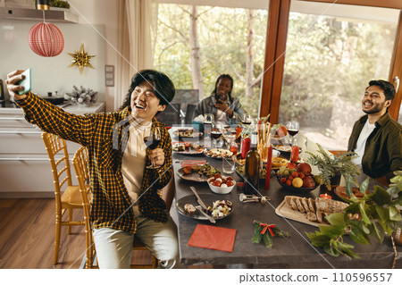 Smiling young friends taking selfie photo holding wine glasses on holiday dinner party at home 110596557