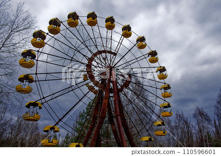 A weathered Ferris wheel stands tall amidst bare trees. 110596601