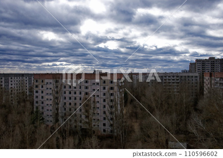Old residential buildings, bare trees in the foreground, and a cloudy sky overhead. Old residential buildings, bare trees in the foreground, and a cloudy sky overhead. 110596602