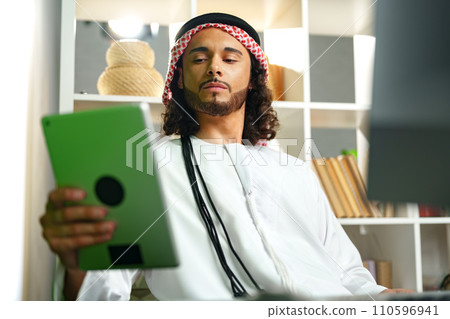 Young Arab businessman using digital tablet in an office Young Arab businessman using digital tablet in an office 110596941
