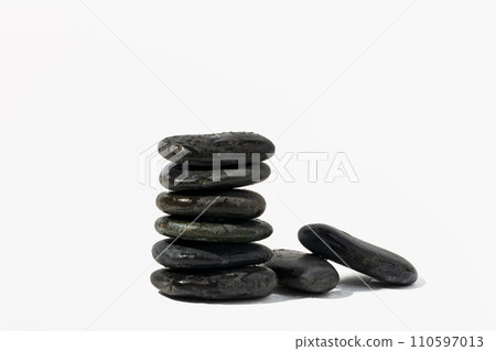 Stacked black spa pebbles on white background 110597013