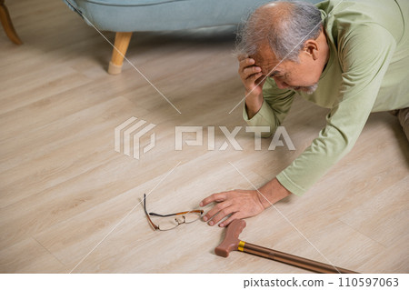 Asian elderly man retired headache after fall down, Sick senior old man falling down lying on floor at house alone with wooden cane walking stick in living room, Health care and medicine concept 110597063