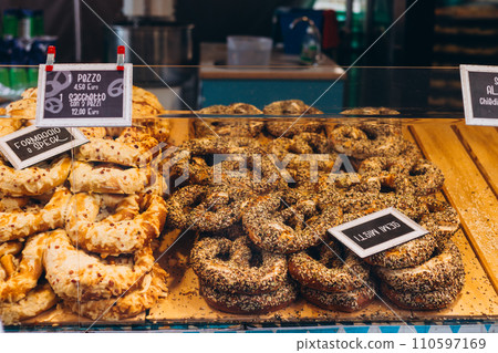 Assortment of pretzel and bagel buns on a showcase counter at bakery shop. Tasty snack and fast food commerce 110597169
