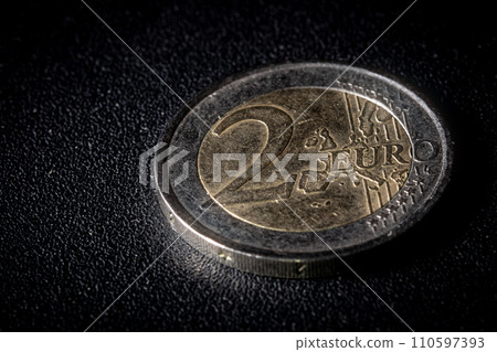 Two euro coin on dark textured background Two euro coin on dark textured background 110597393
