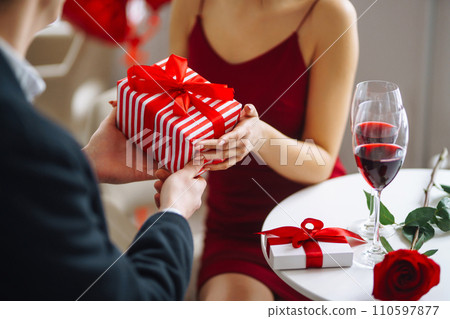 Exchange of gifts. Young couple celebrating Valentine's Day. Romantic evening in a restaurant. 110597877