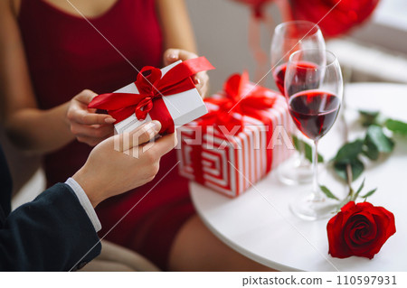 Exchange of gifts. Young couple celebrating Valentine's Day. Romantic evening in a restaurant. Exchange of gifts. Young couple celebrating Valentine's Day. Romantic evening in a restaurant. 110597931