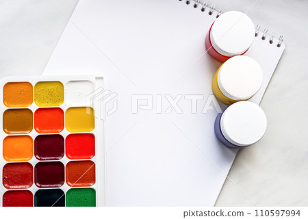 Colorful watercolor or acrylic paints and pencils on a white sheet of paper on a white background. Design studio table top view. Space for text. Colorful watercolor or acrylic paints and pencils on a white sheet of paper on a white background. Design studio table top view. Space for text. 110597994