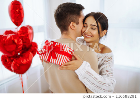 Valentine's Day concept. Lovers give each other gifts. Couple at home celebrating Valentine's Day. Valentine's Day concept. Lovers give each other gifts. Couple at home celebrating Valentine's Day. 110598291