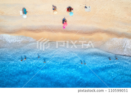 Aerial view of blue sea, sandy beach, umbrellas, swimming people 110599051