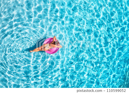 Aerial view of a young woman swimming with swim ring in blue sea 110599052