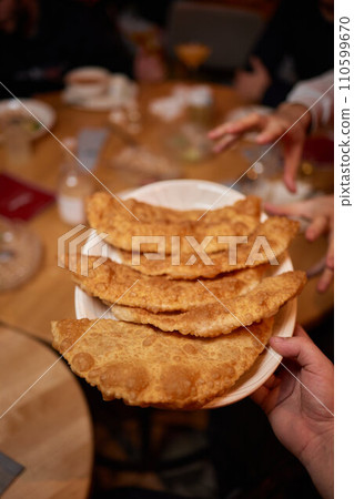 Traditional Cornish pasty filled with beef meat, potato and vegetables on black plate 110599670