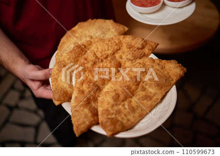 Traditional Cornish pasty filled with beef meat, potato and vegetables on black plate 110599673