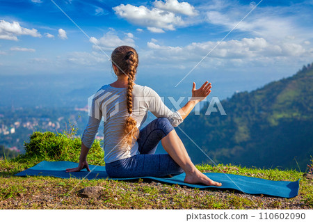 Woman practices yoga asana outdoors 110602090