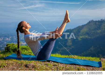 Woman doing Ashtanga Vinyasa Yoga asana Navasana - boat pose 110602095