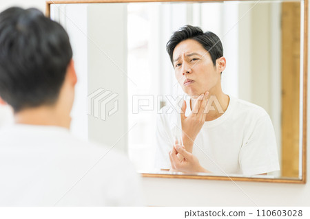 一名中年男子戴上口罩後檢查皮膚是否粗糙。 一名中年男子戴上口罩後檢查皮膚是否粗糙。 110603028