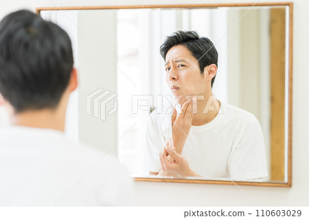 一名中年男子戴上口罩後檢查皮膚是否粗糙。 110603029
